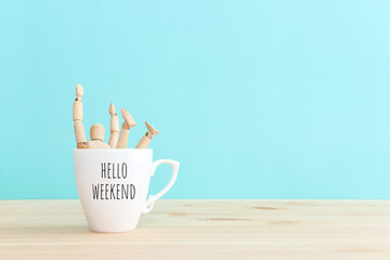 Wooden figure jumping from coffee mug with the text hello weekend