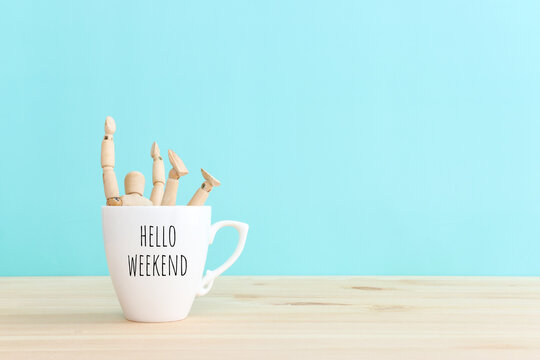 Wooden figure jumping from coffee mug with the text hello weekend