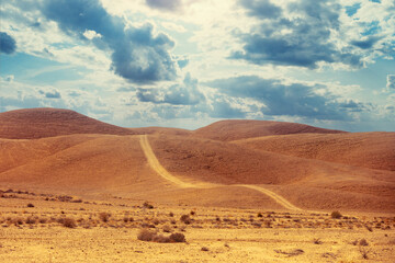 Fototapeta na wymiar Desert landscape with blue sky. Dirt road in mountains