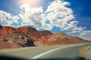 Highway in the mountain desert. Sandstone mountains along the road. View from car