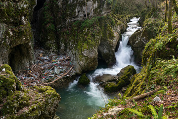 Waterfall with mossy rocks in mountain canyon and plastic waste problem, Svrakava river near Banja Luka