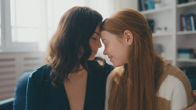 Beautiful mother and teenage daughter leaning foreheads together, family bond