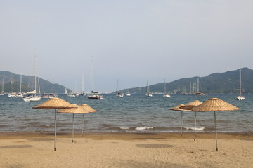 View of the city beach of Marmaris with beach umbrellas on the background of yachts, Marmaris, Turkey, May 2023.