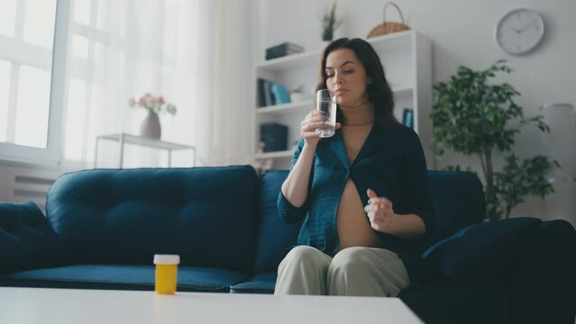 Woman expecting baby taking supplements for pregnant women, pregnancy vitamins
