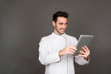 Smiling young male chef using tablet in studio