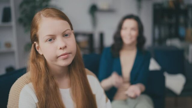 Teenage girl rolls eyes while mother talks on background, puberty, adolescence