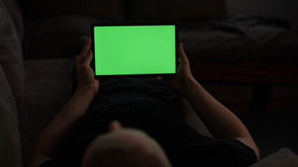 Naklejka premium Man at home lying on a couch with tablet pc with green screen