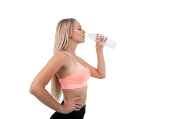 A sporty woman in a pink top drinks water after a workout on a white background..