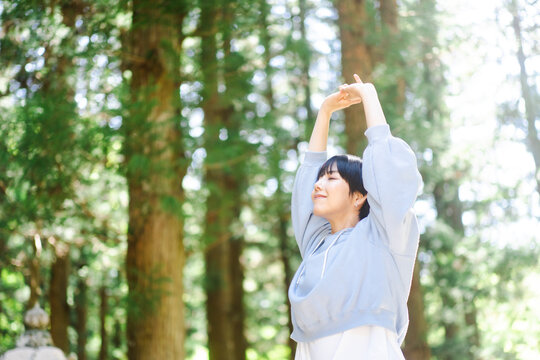 新緑の美しい森で森林浴をしている日本人女性	