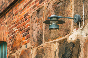 Outdoor electric light lamp attached to an old building facade in Halmstad, Sweden.