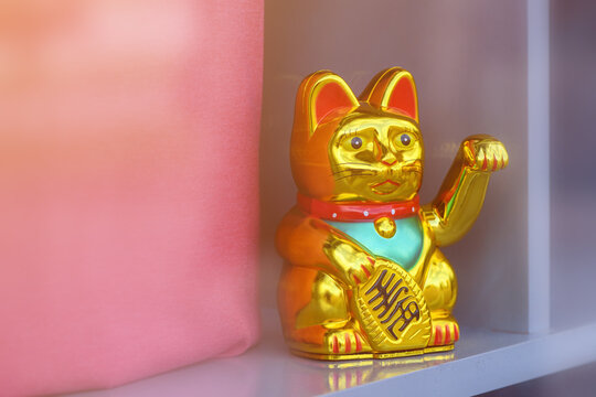 Maneki neko, japanese waving cat adorning the storefront of a trendy clothes boutique. This lucky feline figurine is popular symbol of good fortune and prosperity in Asian culture.