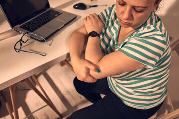 Woman with elbow pain while working on a laptop at home.
