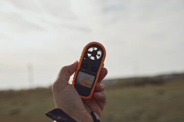 Person holding modern digital anemometer outdoors for measuring wind speed, temperature, humidity...