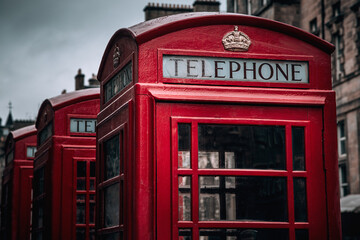 A row of classic British phone boxes on The Royal Mile, Edinburgh, Scotland. Retro effect close up in dark and moody tones.