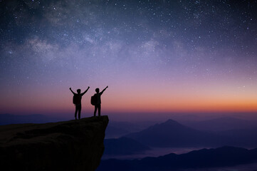 Silhouette of couple young traveler and backpacker watched the star and milky way alone on top of the mountain. He enjoyed traveling and was successful when he reached the summit.