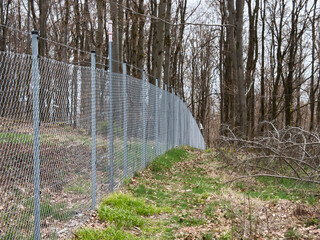 large chain link fence goes through the forest