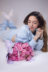 A beautiful woman lay down next to a bouquet of peony roses. The florist creates a pink beautiful bouquet of mixed flowers. Fresh bouquet. Master classes and floristry courses. Flower delivery.