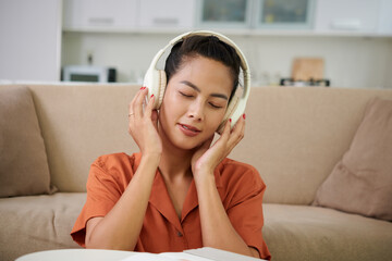 Portrait of young woman closing eyes when enjoying good music in headphones