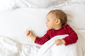 Infant baby sleeping in bed with white linen.