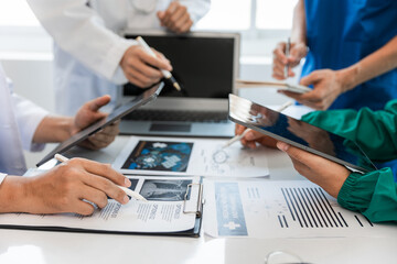 Medical team meeting with doctors in white lab coats and surgical gowns sitting at table discussing patient history. success of medical health care The concept of working with a doctor. Close up.