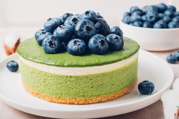 Layered ice cream matcha cheesecake with fresh blueberries. Gluten free no bake summer dessert. Healthy sweet food.