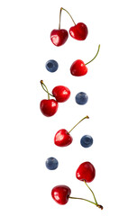 Falling cherry and blueberries isolated on white. Cherry fruit and blueberries with copy space for text. Sweet berries and fruits isolated on white background cutout. With clipping path.