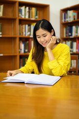 Serene female student reading book in a library for studying and research. Education, learning, knowledge and university