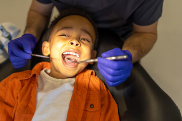 Dentist examining oral cavity of a little dark-skinned boy