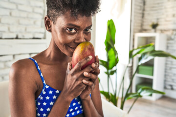 Admiring a mango, an African woman in sportswear embraces a healthy lifestyle with zest.
