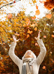 Older woman playing in autumn leaves