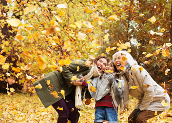 Three generations of women playing in autumn leaves