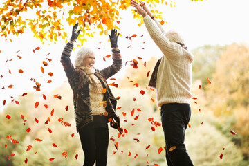 Older couple playing in autumn leaves