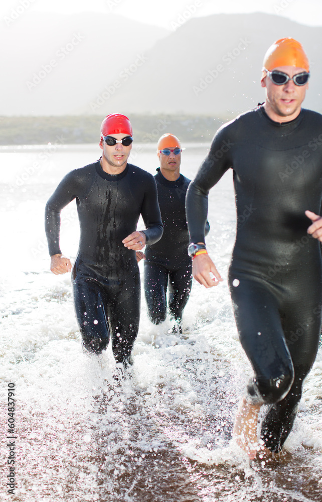 Canvas Prints Triathletes in wetsuits running in waves