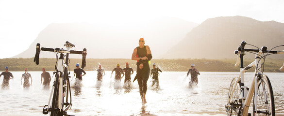 Triathletes running to bicycles on beach