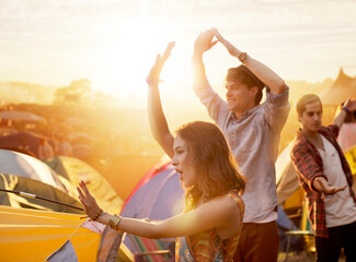 Friends dancing outside tents at music festival