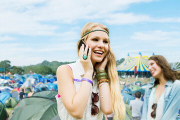 Woman talking on cell phone outside tents at music festival