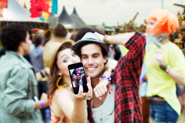 Couple taking self-portrait with camera phone at music festival