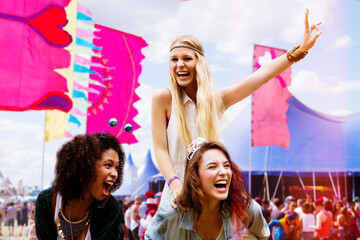 Woman piggybacking enthusiastic friend at music festival