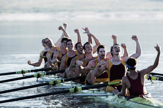 Rowing team celebrating in scull on lake