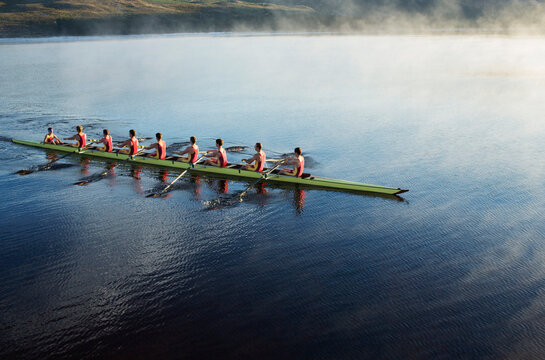 Rowing crew rowing scull on lake
