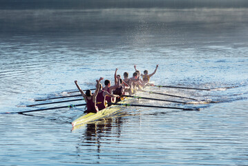 Rowing team celebrating in scull on lake - obrazy, fototapety, plakaty