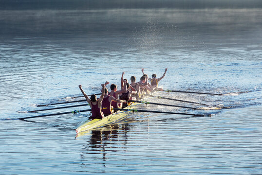 Rowing team celebrating in scull on lake