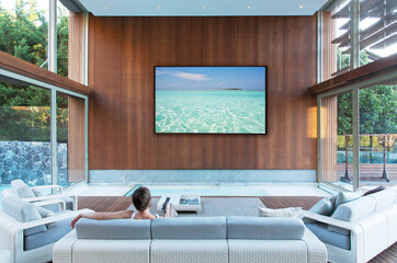 Woman watching large flat screen TV in modern living room