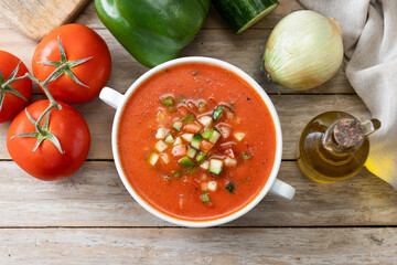 Traditional Spanish gazpacho soup in bowl on wooden table. Top view