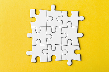 Fototapeta premium Pieces of a puzzle united among themselves on a yellow background.