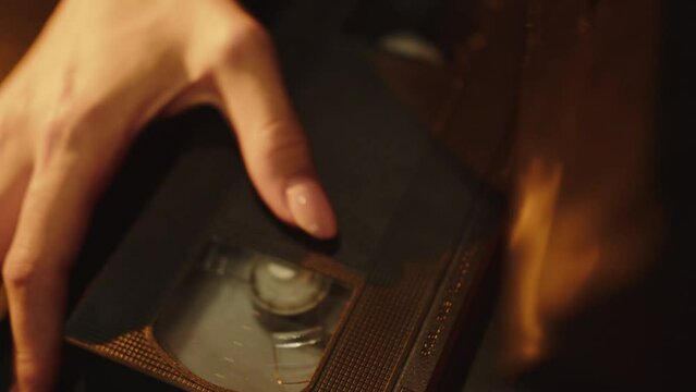 hands sorting through old video cassettes in the evening lighting