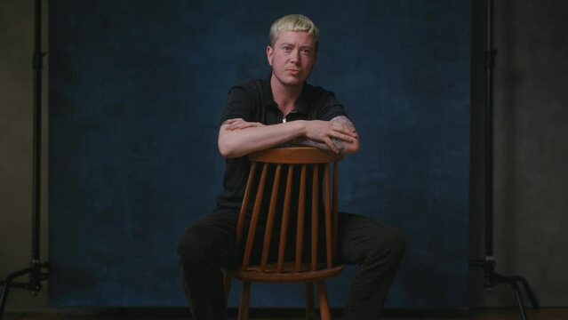 Gay man with arms folded sitting on chair