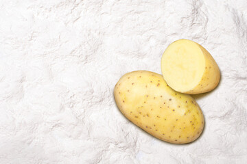 Fresh potato on potato starch (potato powder) texture background. Top view. Flat lay.