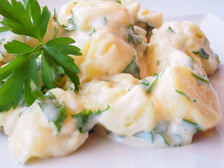 Close-up of potatoes with Aioli garlic sauce, garnished with parsley and toast bread on the board