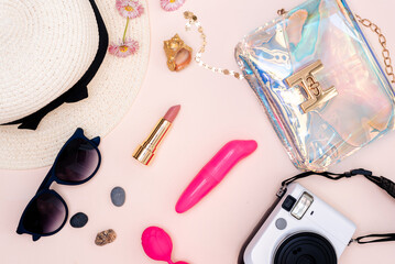 summer travel accessories. women's set of adult toys, camera, hat, glasses and top view on a light background.